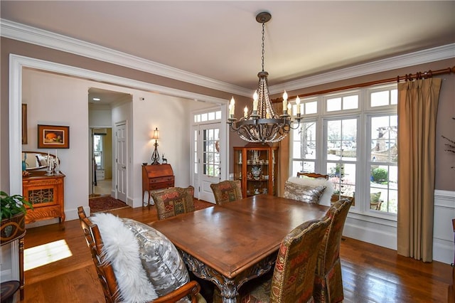 dining space featuring crown molding, plenty of natural light, dark wood finished floors, and an inviting chandelier