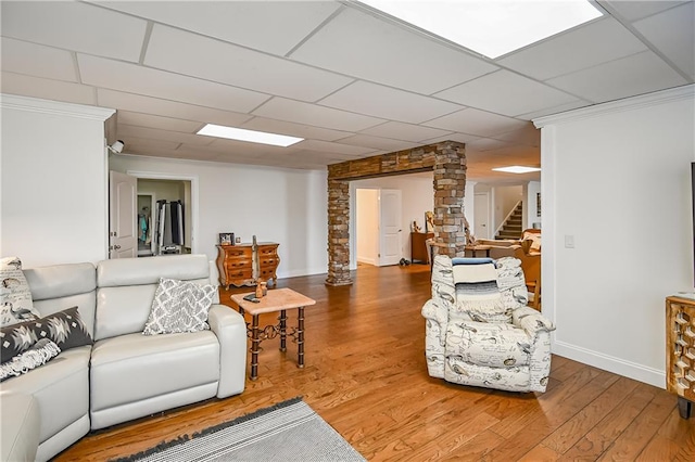 living room with baseboards, stairs, wood finished floors, decorative columns, and a drop ceiling