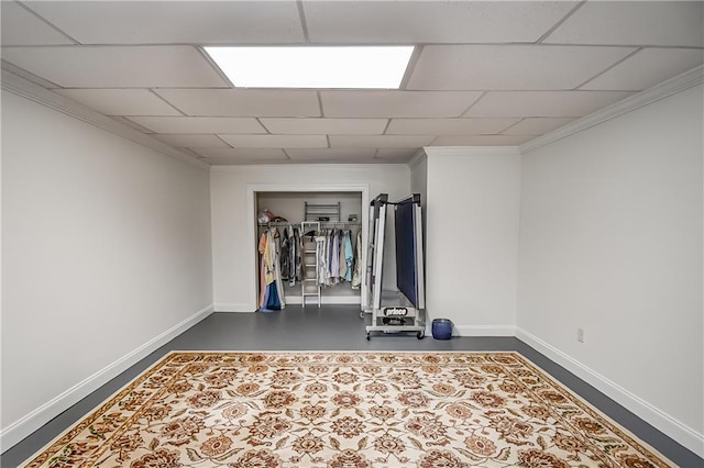 exercise area featuring baseboards, crown molding, and a paneled ceiling