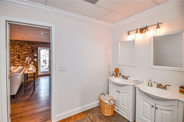 bathroom featuring two vanities, baseboards, ornamental molding, and a sink