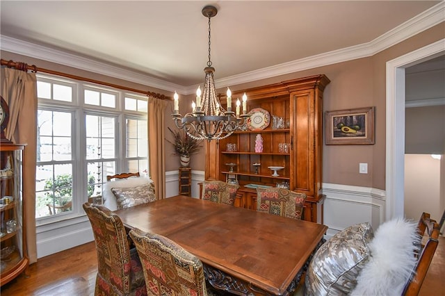 dining space with wood finished floors, crown molding, and an inviting chandelier