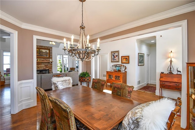 dining area with ornamental molding, wood finished floors, and a fireplace