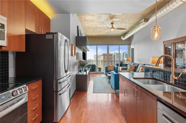 943 Peachtree St NE Unit 1910, Atlanta, GA 30309 - kitchen with a sink, appliances with stainless steel finishes, light wood finished floors, a ceiling fan, and brown cabinetry