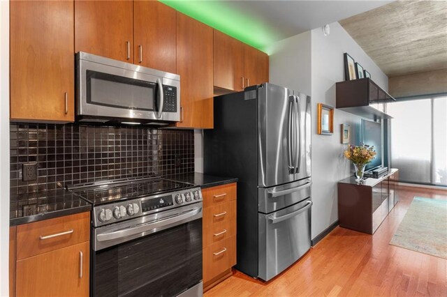 943 Peachtree St NE Unit 1910, Atlanta, GA 30309 - kitchen featuring light wood-type flooring, backsplash, appliances with stainless steel finishes, and brown cabinets