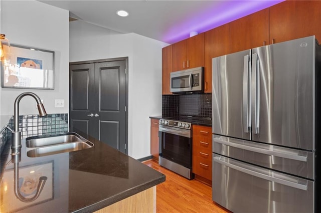 943 Peachtree St NE Unit 1910, Atlanta, GA 30309 - kitchen with brown cabinets, decorative backsplash, a sink, appliances with stainless steel finishes, and light wood-style floors