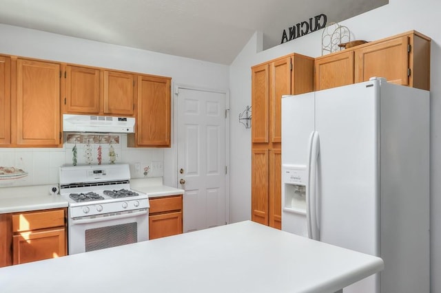 kitchen featuring under cabinet range hood, white appliances, backsplash, and light countertops