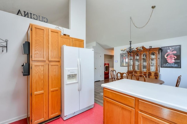 kitchen featuring light countertops, white refrigerator with ice dispenser, and a chandelier