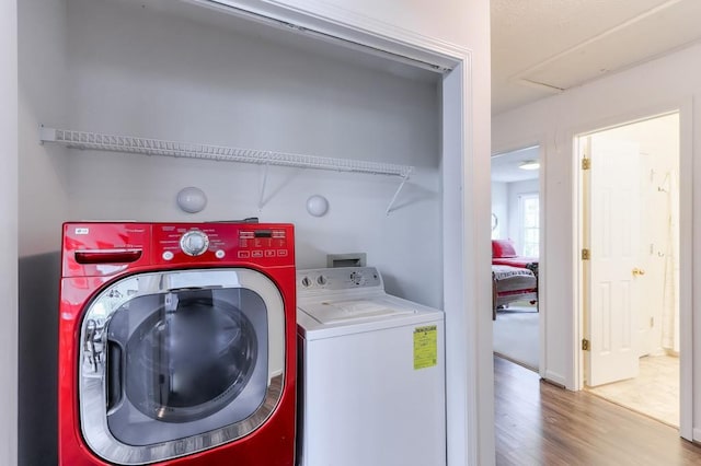 laundry room with laundry area, washing machine and dryer, and wood finished floors