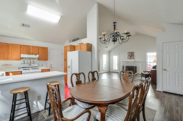 dining space featuring visible vents, high vaulted ceiling, dark wood-style floors, an inviting chandelier, and a fireplace