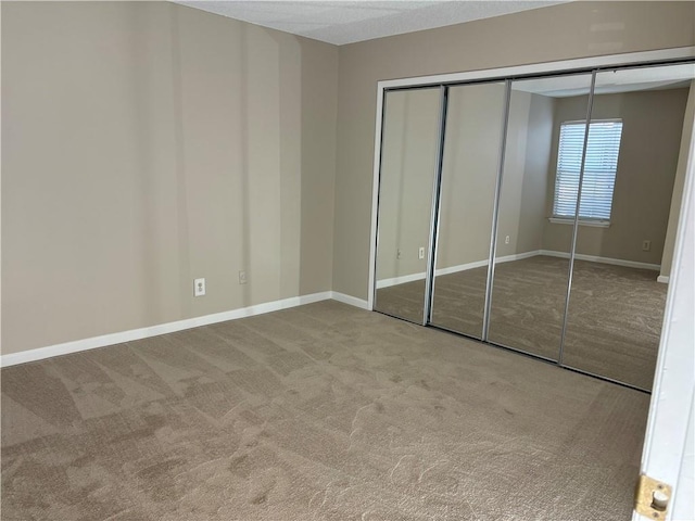 unfurnished bedroom featuring carpet, a closet, and baseboards