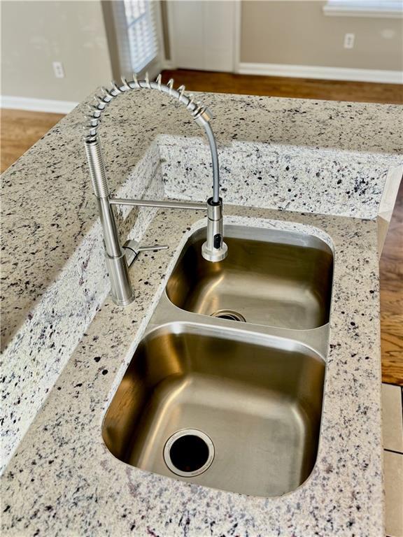 interior details featuring a sink, baseboards, and light stone counters