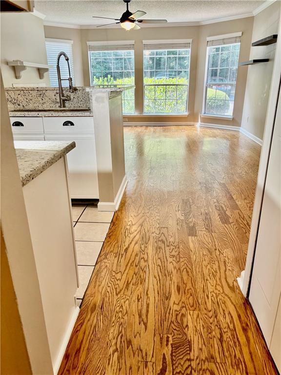 kitchen featuring white cabinets, ornamental molding, a ceiling fan, and a textured ceiling