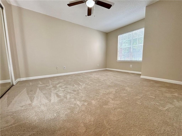 carpeted spare room featuring baseboards, a textured ceiling, and ceiling fan