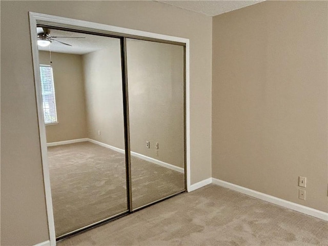 unfurnished bedroom featuring a closet, ceiling fan, baseboards, and carpet floors