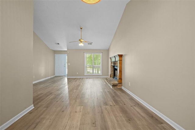 unfurnished living room with light wood-type flooring, vaulted ceiling, ceiling fan, and a fireplace