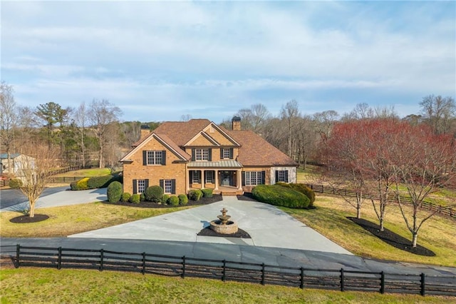 colonial-style house featuring a fenced front yard, concrete driveway, and a chimney