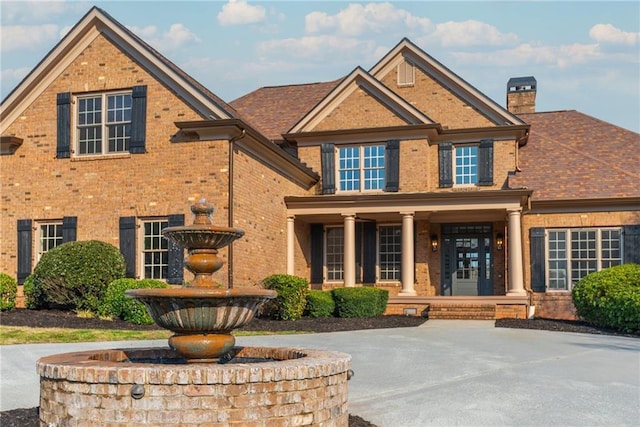 view of front of house featuring brick siding and a chimney