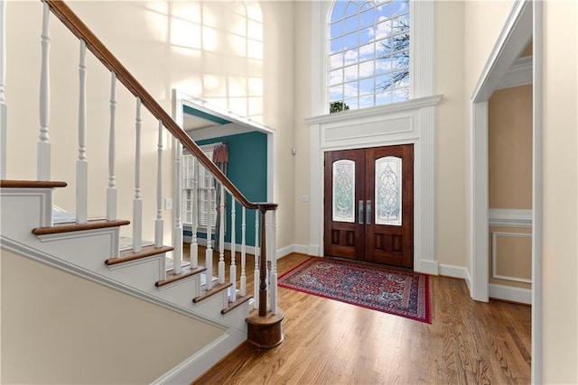 foyer with hardwood / wood-style flooring, a high ceiling, and french doors