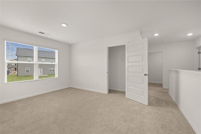 unfurnished bedroom with light colored carpet and a closet