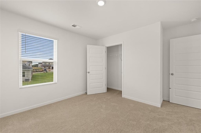 unfurnished bedroom with light carpet and a closet