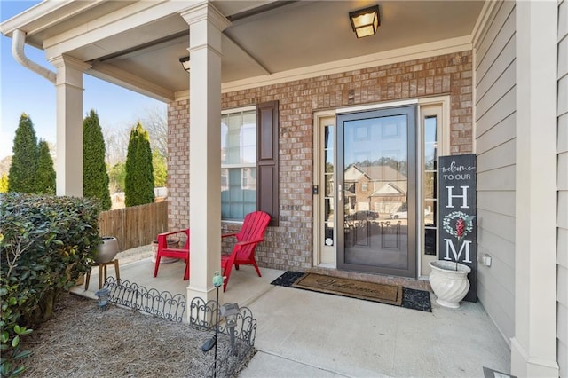 property entrance with covered porch, brick siding, and fence