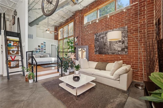 living room with ceiling fan, a towering ceiling, concrete floors, and brick wall