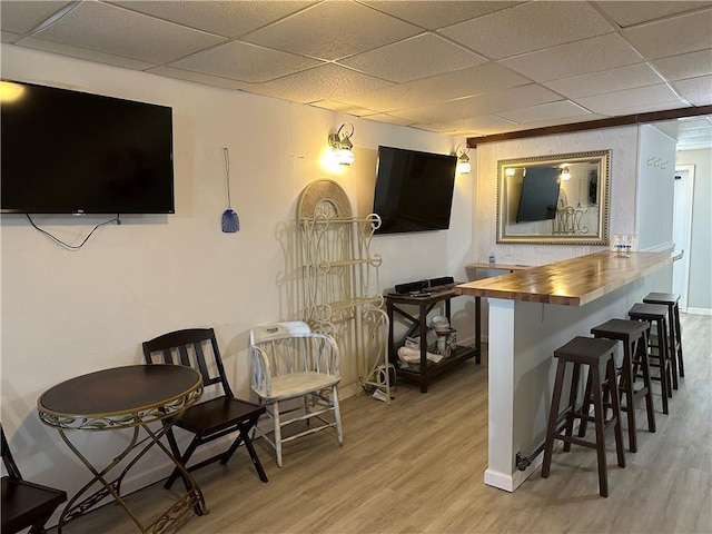 bar with baseboards, light wood-style flooring, and a paneled ceiling