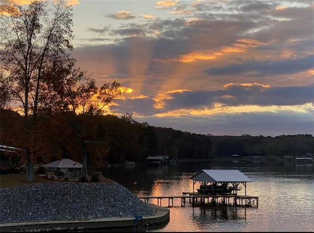 water view with a boat dock, boat lift, and a forest view