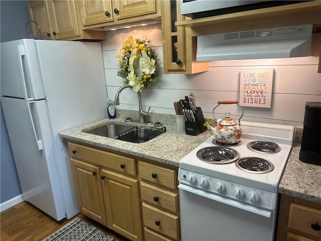 kitchen featuring a sink, white appliances, brown cabinets, wood finished floors, and light stone counters