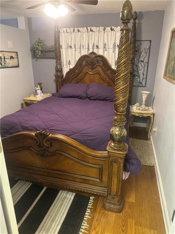 bedroom featuring a ceiling fan, a textured ceiling, wood finished floors, and baseboards