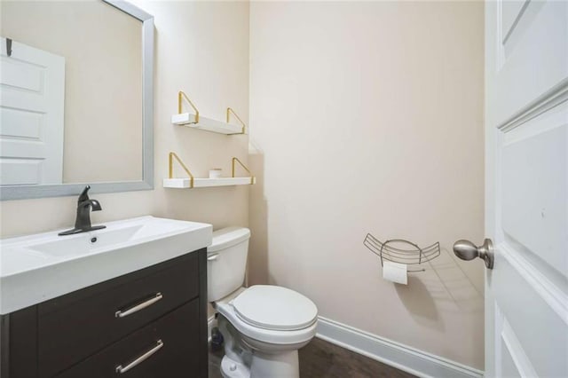 half bathroom featuring baseboards, vanity, and toilet