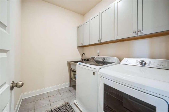 clothes washing area featuring light tile patterned floors, separate washer and dryer, cabinet space, and baseboards