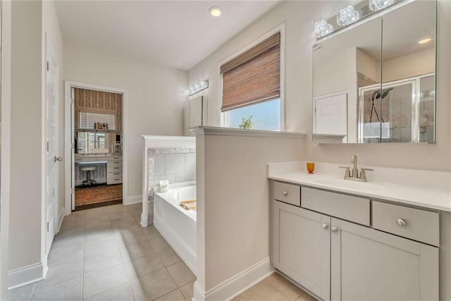 bathroom with a stall shower, vanity, tile patterned flooring, baseboards, and a bath