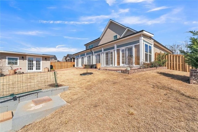 back of property featuring a sunroom, french doors, a fenced backyard, and a patio