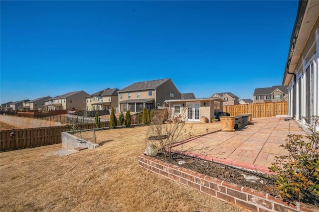 view of yard featuring a residential view, french doors, a fenced backyard, and a patio