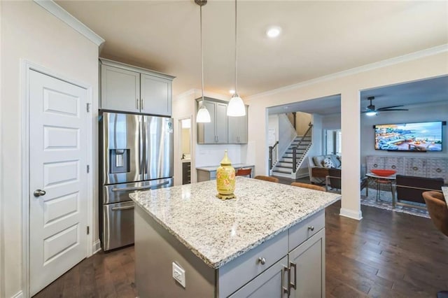 kitchen featuring stainless steel fridge, a kitchen island, light stone countertops, gray cabinets, and crown molding