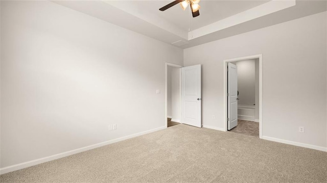 unfurnished bedroom featuring a raised ceiling, carpet, and ceiling fan