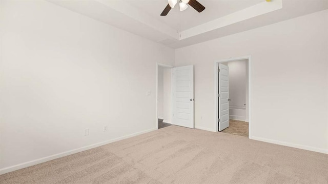 unfurnished bedroom featuring a tray ceiling, light colored carpet, and ceiling fan