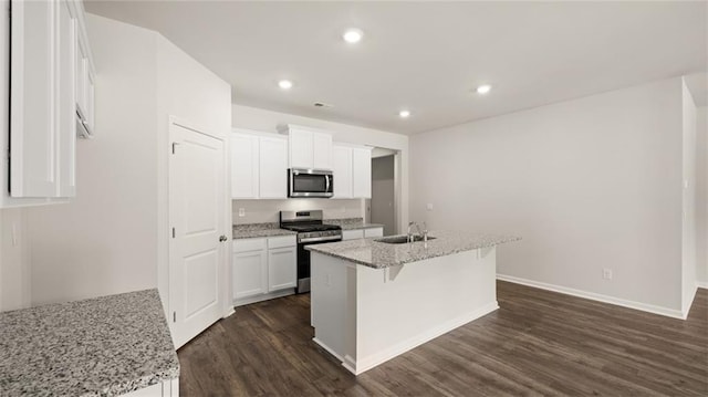 kitchen with a kitchen island with sink, light stone counters, stainless steel appliances, and white cabinetry