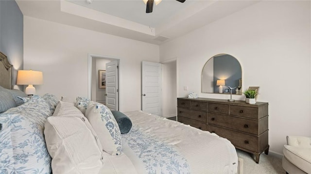 carpeted bedroom with ceiling fan and a raised ceiling