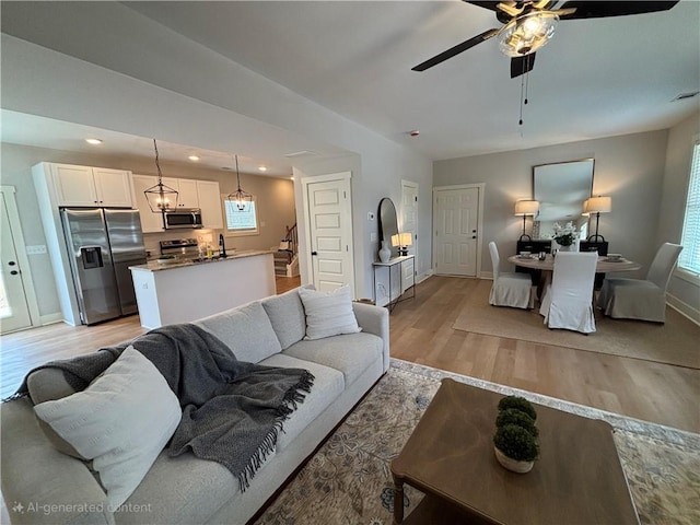 living room with baseboards, a ceiling fan, stairs, light wood-style floors, and recessed lighting