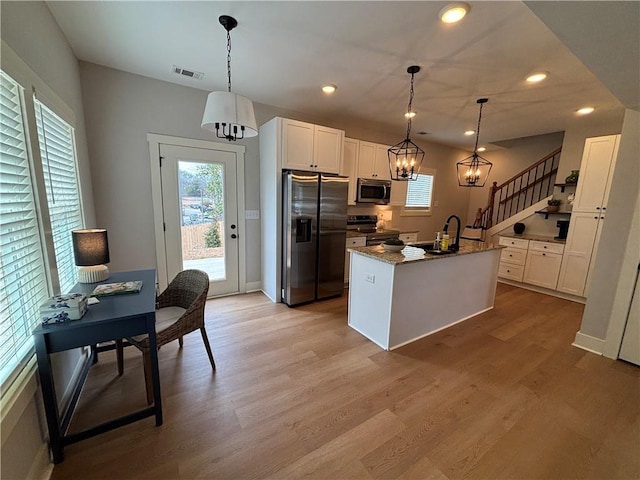 kitchen with visible vents, appliances with stainless steel finishes, light wood-style floors, white cabinets, and a sink