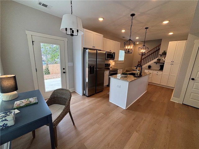 kitchen with appliances with stainless steel finishes, white cabinets, visible vents, and light wood-style flooring