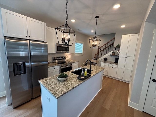 kitchen featuring white cabinets, light wood-style floors, stainless steel appliances, and a sink