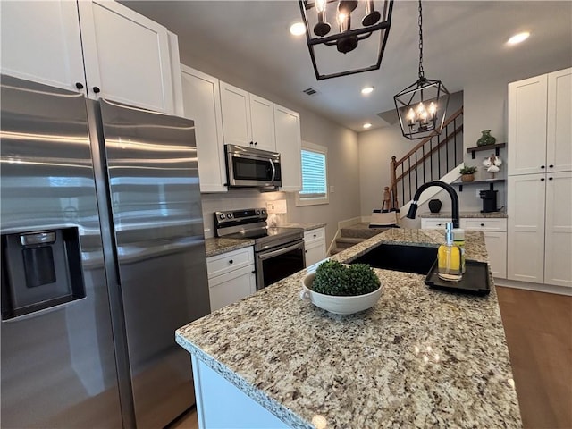 kitchen with recessed lighting, stainless steel appliances, a sink, white cabinets, and light stone countertops