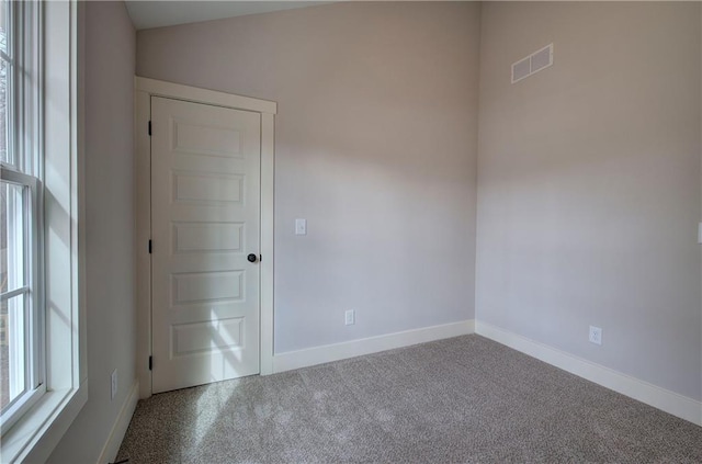 carpeted spare room with baseboards and visible vents