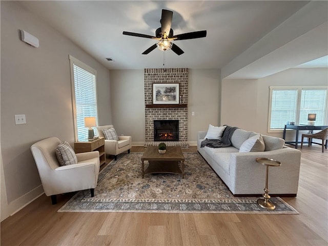 living area with a wealth of natural light, visible vents, baseboards, and wood finished floors