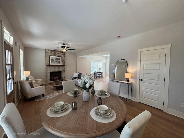 dining area with ceiling fan, a fireplace, baseboards, and wood finished floors