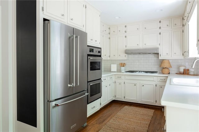 6960 Hunters Branch Dr, Atlanta, GA 30328 - kitchen featuring appliances with stainless steel finishes, light countertops, dark wood-style flooring, and under cabinet range hood