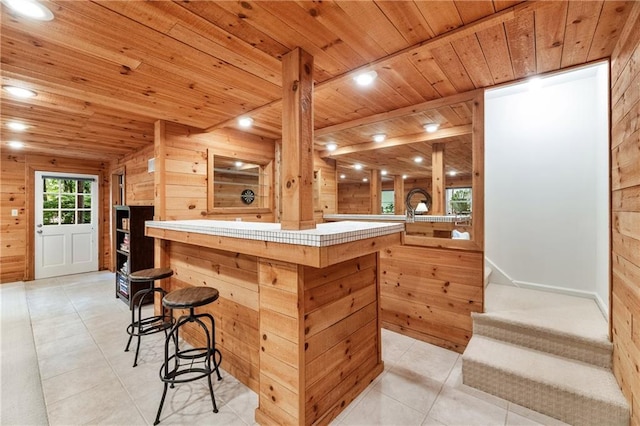 6960 Hunters Branch Dr, Atlanta, GA 30328 - kitchen with tile countertops, wood ceiling, wooden walls, a breakfast bar area, and light tile patterned flooring